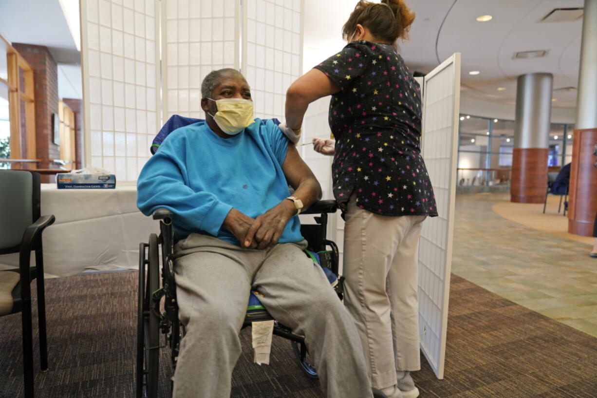 FILE - Edward Williams, 62, a resident at the Hebrew Home at Riverdale, receives a COVID-19 booster shot in New York, Sept. 27, 2021. COVID-19 infections are soaring again at U.S. nursing homes because of the omicron wave, and deaths are climbing too. That's leading to new restrictions on family visits and a renewed push to get more residents and staff members vaccinated and boosted.