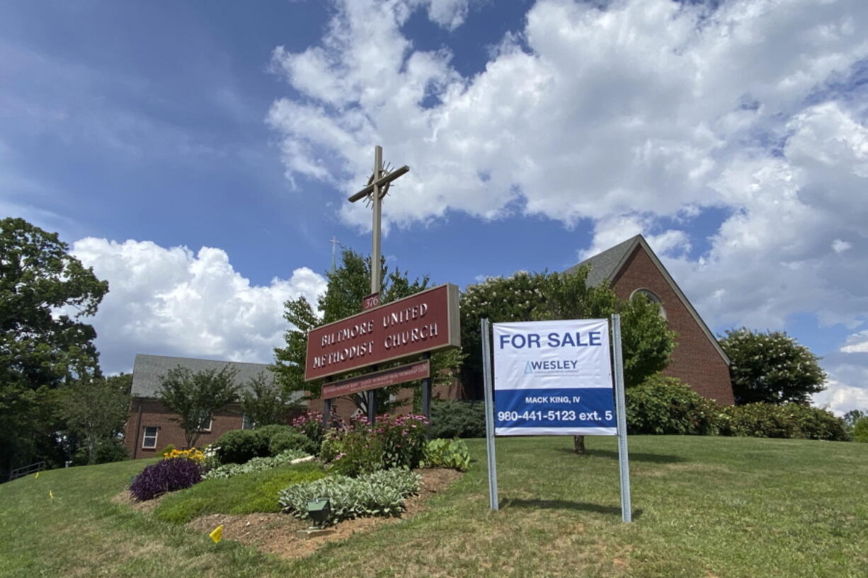 This photo provided by the Rev. Lucy Robbins shows a "For Sale" sign in front of the Biltmore United Methodist Church in Asheville, N.C. in July 2021. Already financially strapped because of shrinking membership and a struggling preschool, the congregation was dealt a crushing blow by the coronavirus. Attendance plummeted, with many staying home or switching to other churches that stayed open the whole time. Gone, too, is the revenue the church formerly got from renting its space for events and meetings. (Rev.