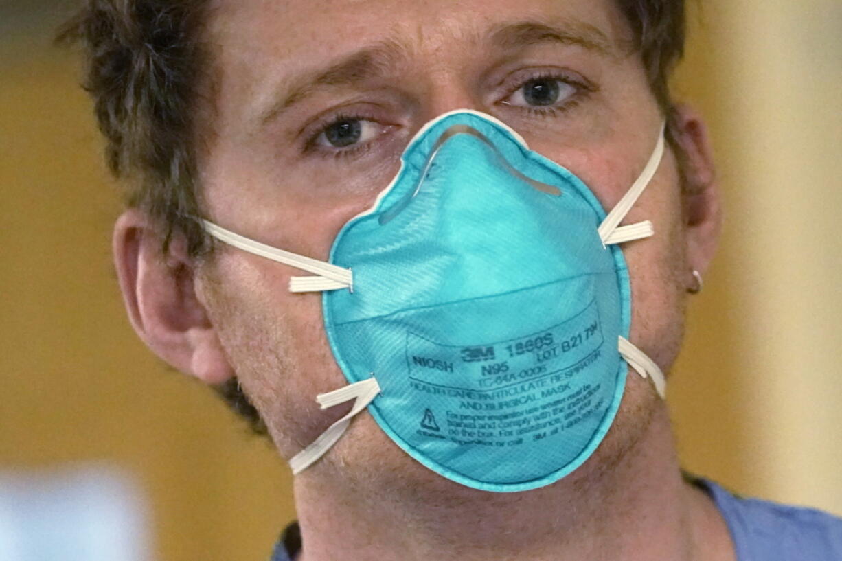 Registered nurse Scott McGieson wears an N95 mask as he walks out of a patient's room in the acute care unit of Harborview Medical Center, Friday, Jan. 14, 2022, in Seattle. Washington Gov. Jay Inslee is deploying 100 members of the state National Guard to hospitals across the state amid staff shortages due to an omicron-fueled spike in COVID-19 hospitalizations. Inslee announced Thursday that teams will be deployed to assist four overcrowded emergency departments at hospitals in Everett, Yakima, Wenatchee and Spokane, and that testing teams will be based at hospitals in Olympia, Richland, Seattle and Tacoma.