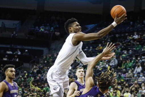 Oregon forward Quincy Guerrier, top, shoots over Washington forward Emmitt Matthews Jr., right, in the first half of an NCAA college basketball game in Eugene, Ore., Sunday, Jan. 23, 2022. (AP Photo/Thomas Boyd)