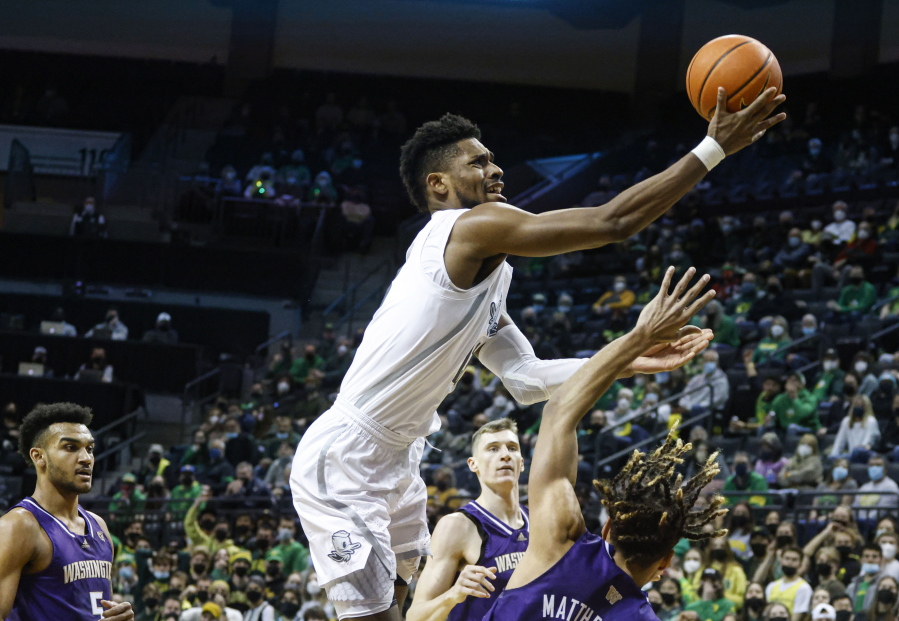 Oregon forward Quincy Guerrier, top, shoots over Washington forward Emmitt Matthews Jr., right, in the first half of an NCAA college basketball game in Eugene, Ore., Sunday, Jan. 23, 2022.