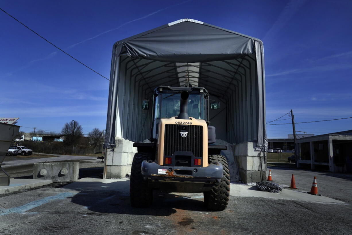 A tractor sits in front of a pile of salt used to create a brine that will help clear road of ice and snow ahead of a winter storm at the GDOT's Maintenance Activities Unit location on Friday, Jan. 14, 2022, in Forest Park, Ga. A winter storm is headed south that could effect much of Georgia through Sunday.