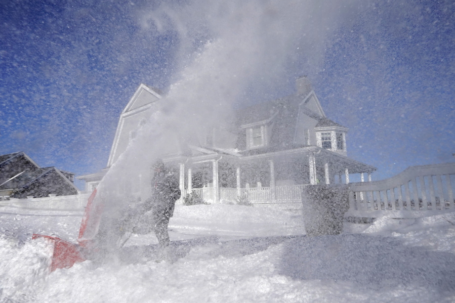 Bill McKelvey, of Scituate, Mass., uses a snow blower to clear snow in front of his home, Sunday, Jan. 30, 2022, in Scituate.
