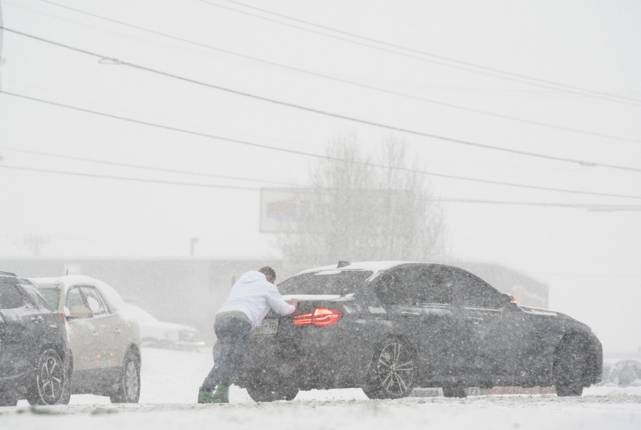 A motorist is pushed through snow by a man on Thursday in Nashville, Tenn. A winter storm blanketed parts of the South with quick-falling snow, freezing rain and sleet Thursday, tying up some roads in Tennessee as the system tracked a path through Appalachia toward the Mid-Atlantic and Northeast.