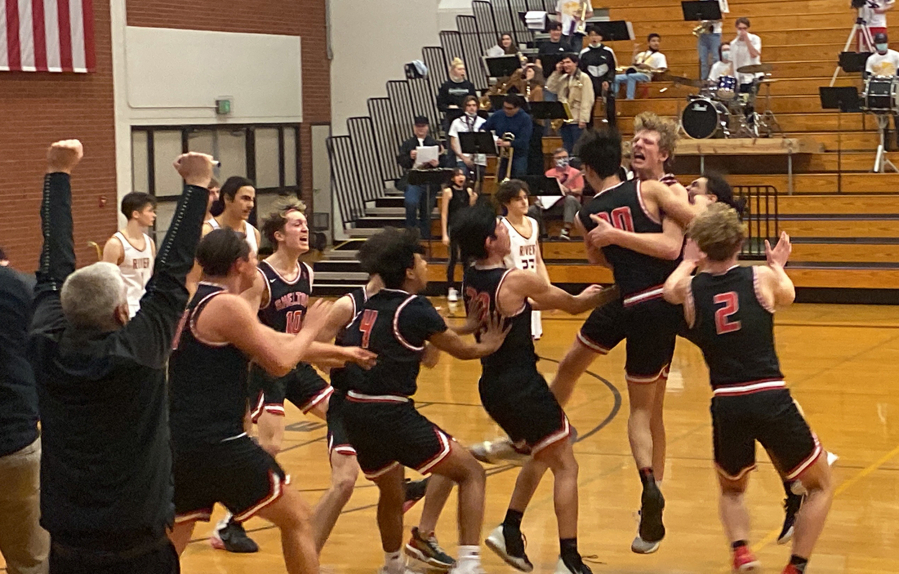 Shelton players mob Tyler Ireland after he made the game-winning shot against Columbia River on Thursday. The 50-48 win by the Shelton ended the Rapids' season.