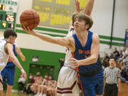 Ridgefield senior Henry Hughes (21) extends for a layup during an elimination loss to W.F. West in the 2A District IV tournament Thursday at Tumwater High School.