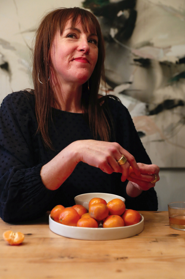 Sarah Hurt peels satsumas over a handmade ceramic bowl and plate Monday, Feb. 14, 2022, at her home in Seattle. Hurt's custom ceramics were made by local artist Sarah Kaye.