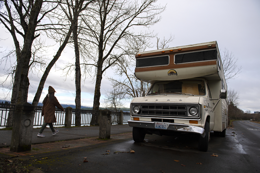 A pedestrian strolls past an abandoned recreational vehicle along Vancouver's Waterfront Renaissance Trail on Tuesday. Derelict vehicles on public property remain a difficult obstacle for towing companies to remove because of their high impound and disposal fee.