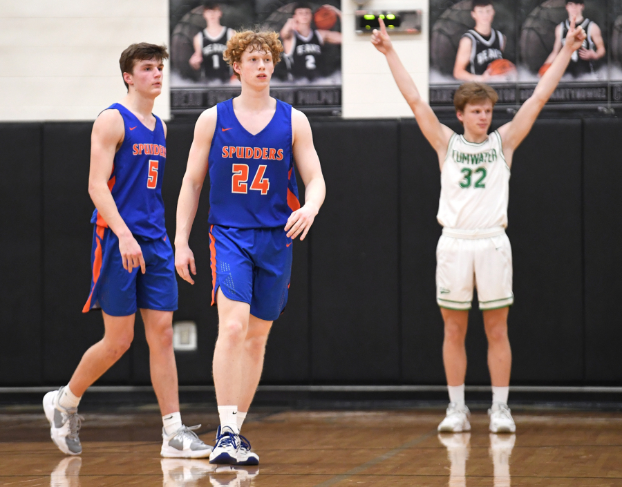 Ridgefield seniors Ty Snider, left, and Joseph Borgmeyer walk off the court while Tumwater senior Adam Overbay celebrates Tuesday, Feb. 15, 2022, after the Spudders' 51-46 loss to Tumwater at Woodland High School.