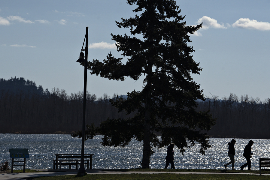 Pedestrians bundle up while taking in a Columbia River view under windy, chilly conditions at the walking path near the Port of Camas Washougal on Tuesday afternoon. Cold temperature records for the day could fall Wednesday.