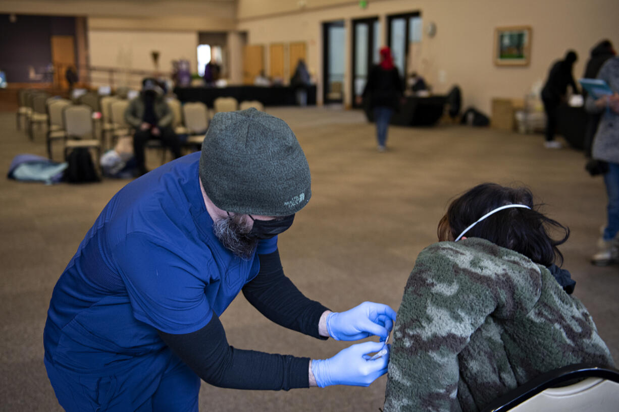 Jordan Bates of Aristo Healthcare, left, administers a dose of COVID-19 vaccine to a person experiencing homelessness at St. Joseph Catholic Church on Thursday. The clinic was part of the Washington State Department of Health's "Health-in-motion Care-a-van", which is a mobile vaccine clinic that made two stops in Vancouver.