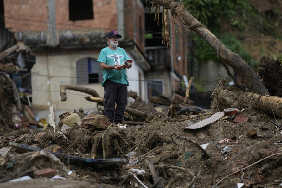 A man with a Bible stands on the debris of homes destroyed by mudslides on the third day of rescue efforts in Petropolis, Brazil, on Friday.