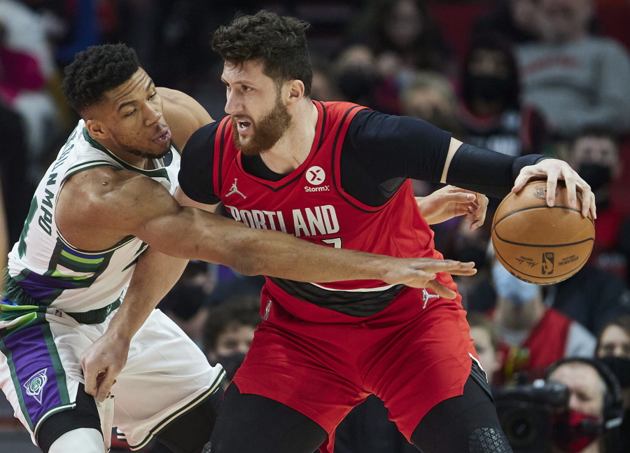 Milwaukee Bucks forward Giannis Antetokounmpo, left, reaches for the ball dribbled by Portland Trail Blazers center Jusuf Nurkic during the first half of an NBA basketball game in Portland, Ore., Saturday, Feb. 5, 2022.