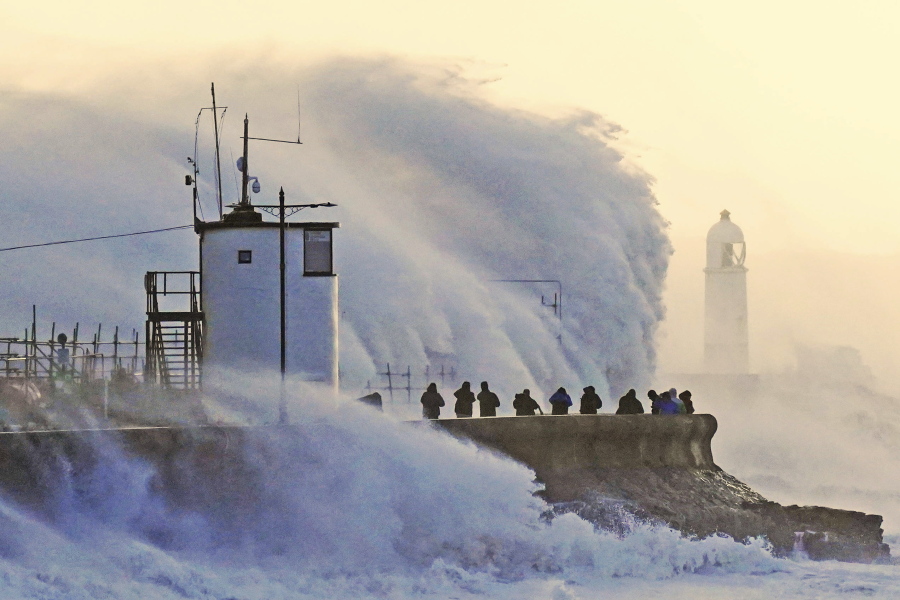 Waves crash against the sea wall and Porthcawl Lighthouse in Porthcawl, Bridgend, Wales,, Britain, as Storm Eunice makes landfall Friday, Feb. 18, 2022. Millions of Britons are being urged to cancel travel plans and stay indoors Friday amid fears of high winds and flying debris as the second major storm this week prompted a rare "red" weather warning across southern England.