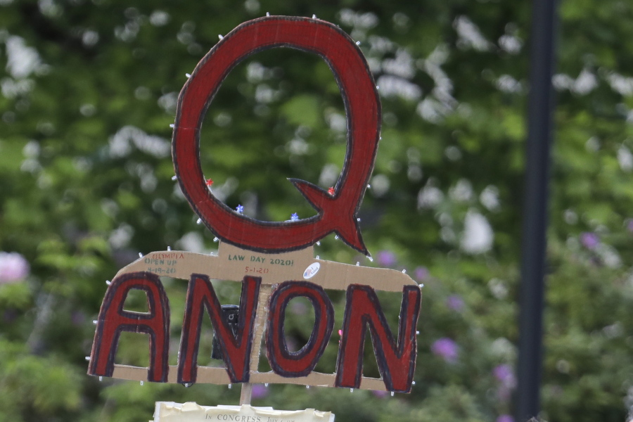 FILE - A person carries a sign supporting QAnon during a protest rally in Olympia, Wash., on May 14, 2020. The QAnon conspiracy theory has been linked to acts of real-world violence, including last year's riot at the U.S. Capitol. In June 2021, a federal intelligence report warned that QAnon adherents could target Democrats and other political opponents for more violence. (AP Photo/Ted S.