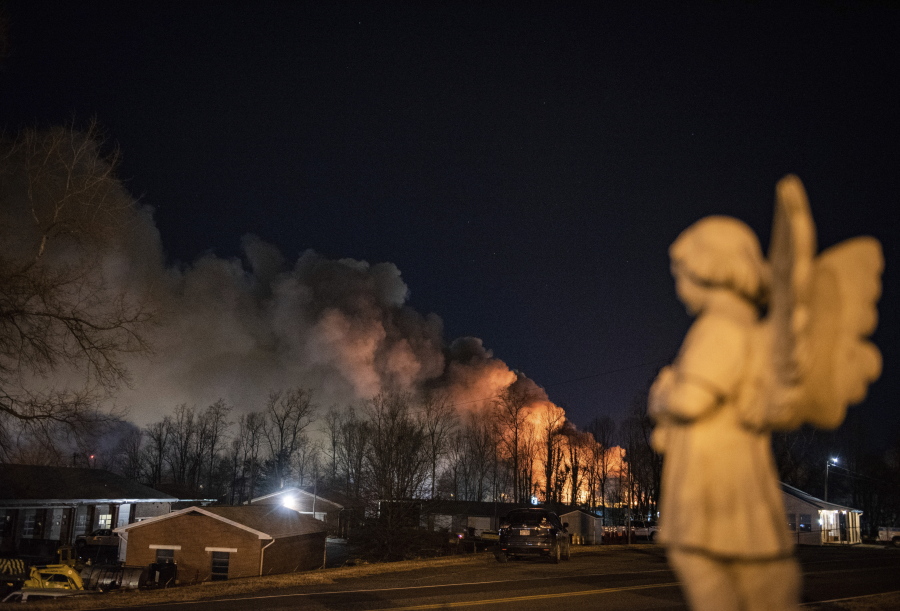 An angel statue faces in the direction of billowing smoke from a fire at the Weaver Fertilizer Plant on Monday, Jan. 31, 2022, in Winston-Salem, N.C.