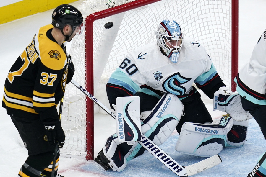 Seattle Kraken goaltender Chris Driedger (60) looks for the shot as the puck sails over his shoulder for a goal by Boston Bruins right wing David Pastrnak during the second period of an NHL hockey game, Tuesday, Feb. 1, 2022, in Boston. At left is Boston Bruins center Patrice Bergeron (37).