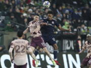 Portland Timbers forward Jaroslaw Niezgoda and New England Revolution defender Brandon Bye jump up to head the ball during the first half of an MLS soccer match, Saturday, Feb. 26, 2022, in Portland, Ore.