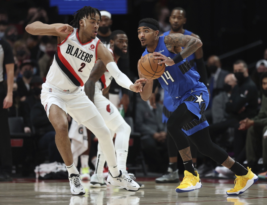 Orlando Magic guard Gary Harris,right, looks to pass the ball as Portland Trail Blazers forward Trendon Watford, left, defends during the first half of an NBA basketball game in Portland, Ore., Tuesday, Feb. 8, 2022.