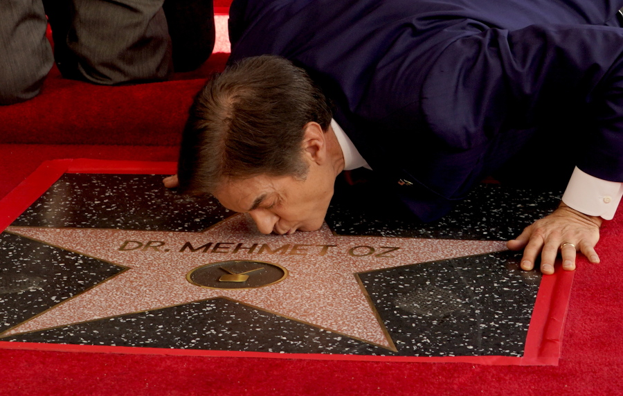 Mehmet Oz, the former host of "The Dr. Oz Show," kisses his new star on the Hollywood Walk of Fame during a ceremony on Friday, Feb. 11, 2022, in Los Angeles.