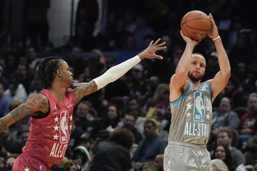 Golden State Warriors' Stephen Curry, right, shoots for three as Memphis Grizzlies' Ja Morant defends during the second half of the NBA All-Star basketball game, Sunday, Feb. 20, 2022, in Cleveland.