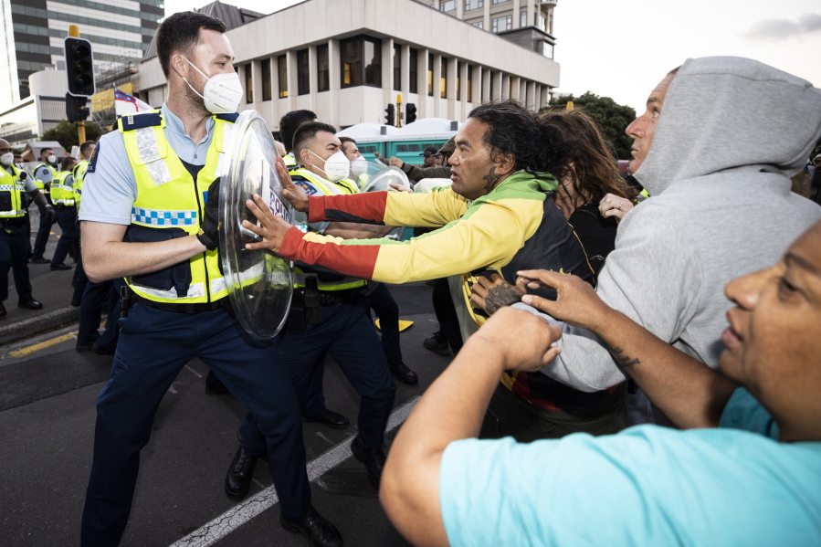 Police and protesters clash in Wellington, New Zealand, Tuesday, Feb. 22, 2022, as police tightened a cordon around a protest convoy that has been camped outside Parliament for two weeks. The protesters, who oppose coronavirus vaccine mandates and were inspired by similar protests in Canada, appear fairly well organized after trucking in portable toilets, crates of donated food, and bales of straw to lay down when the grass turned to mud.