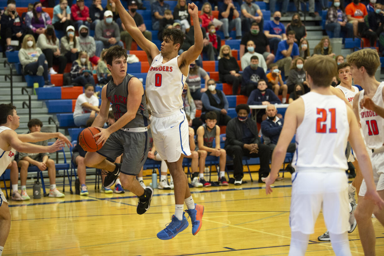 Johnnie Stallings of Black Hills (left) looks to make a pass as Ridgefield’s Sid Bryant (0) defends during Ridgefield’s 54-40 win over the Wolves in the first round of the 2A district boys basketball tournament at Ridgefield.