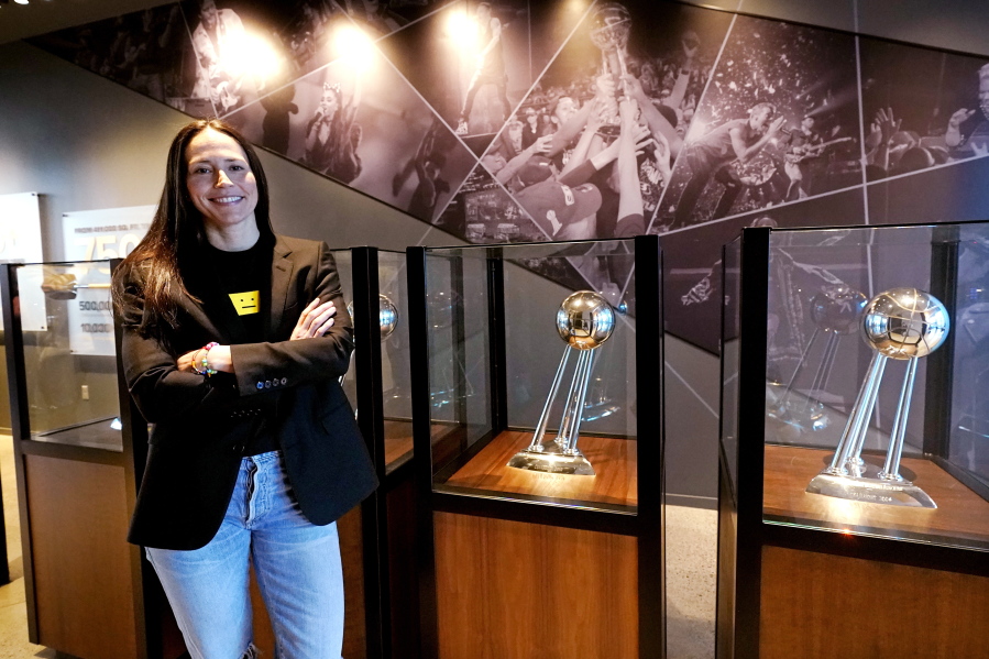 Seattle Storm guard Sue Bird poses for a photo with team championship trophies after a news conference where she talked about her return for one more WNBA basketball season Tuesday, Feb. 22, 2022, in Seattle. Bird, a four-time WNBA champion, 12-time All-Star selection and the oldest player in the league at 41, said all signs are pointing toward the 2022 season being her last in the WNBA, but does not want the upcoming season to be a farewell tour.