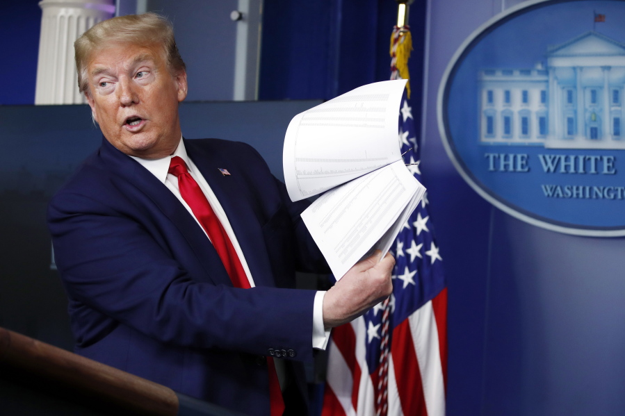 FILE - President Donald Trump holds up papers as he speaks about the coronavirus in the James Brady Press Briefing Room of the White House, April 20, 2020, in Washington. As president, Donald Trump never liked to leave a paper trail. He avoided email, admonished aides to stop taking notes during meetings and ripped up documents when he finished with them.  But Trump was unwilling to part with some of his administration's records when he left the White House last year, whisking them away to Mar-a-Lago, his Florida resort.