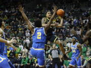 Oregon guard Jacob Young, center right, shoots against UCLA forward Cody Riley (2) in the first half of an NCAA college basketball game in Eugene, Ore., Thursday, Feb. 24, 2022.