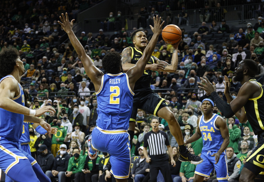 Oregon guard Jacob Young, center right, shoots against UCLA forward Cody Riley (2) in the first half of an NCAA college basketball game in Eugene, Ore., Thursday, Feb. 24, 2022.
