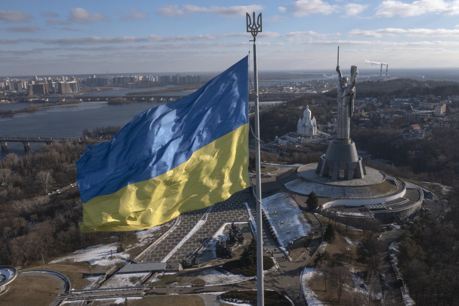 A view of Ukraine's national flag waves above the capital with the Motherland Monument on the right, in Kyiv Sunday, Feb. 13, 2022. Some airlines have halted or diverted flights to Ukraine amid heightened fears that an invasion by Russia is imminent despite intensive weekend talks between the Kremlin and the West.
