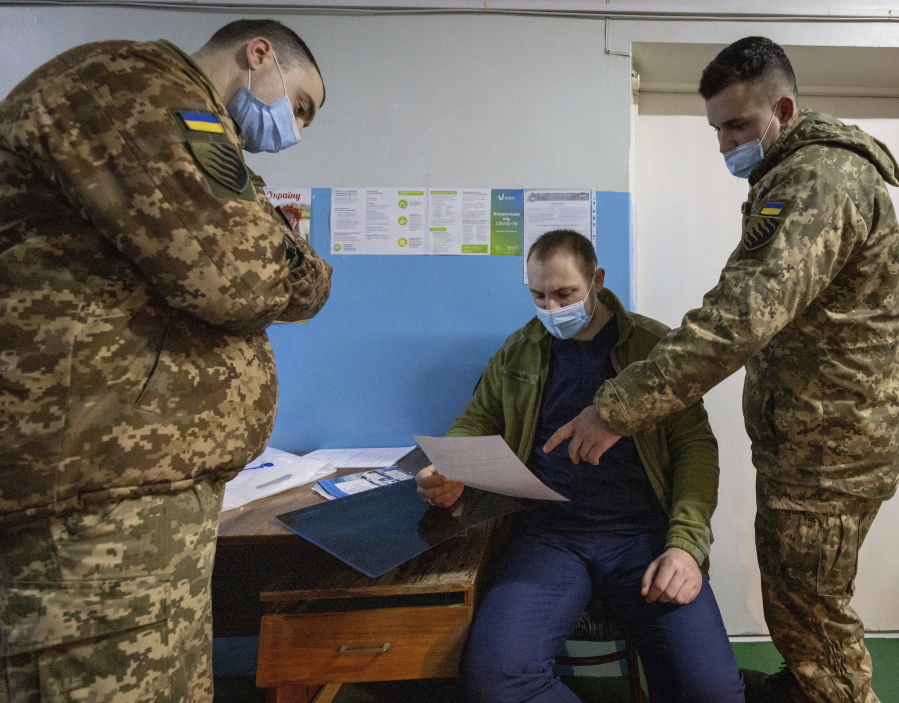 Ukrainian military medical personnel explain the contents of a paper to a patient at the Military Mobile Hospital 66 in Pokrovsk, eastern Ukraine, on Wednesday, Feb. 9, 2022. The 100-bed mobile hospital located nearly 48 km (30 miles) from the line of separation between Ukraine-held territory and rebel-held territory was established in 2015 following conflict with Russia. Several hundred support staff under Medical Forces Command tend to patients the hospital receives from the frontline as well as acute civilian injuries.