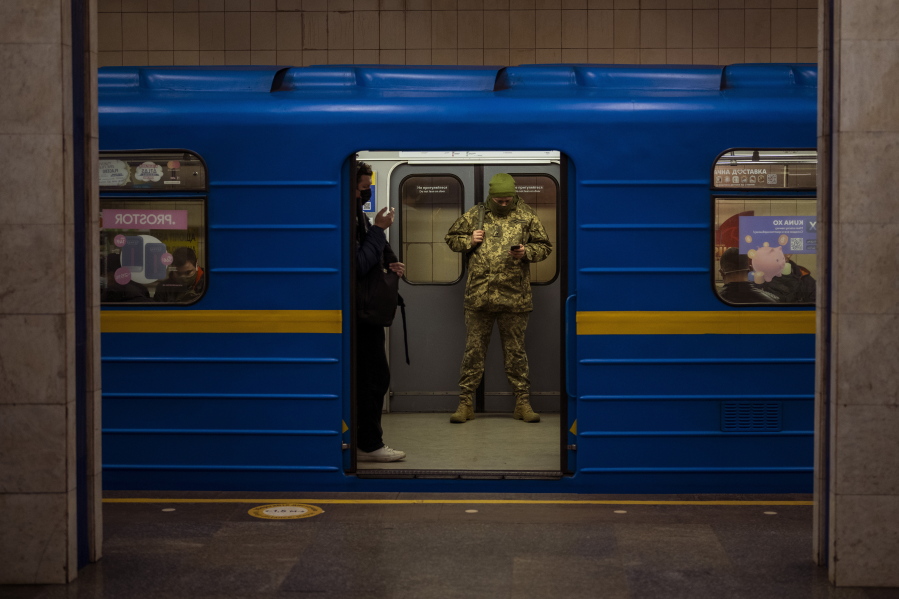 A Ukrainian army officer looks at his phone in a local train in Kyiv, Ukraine, Wednesday, Feb. 23, 2022. Ukraine urged its citizens to leave Russia as Europe braced for further confrontation Wednesday after Russia's leader received authorization to use military force outside his country and the West responded with a raft of sanctions.