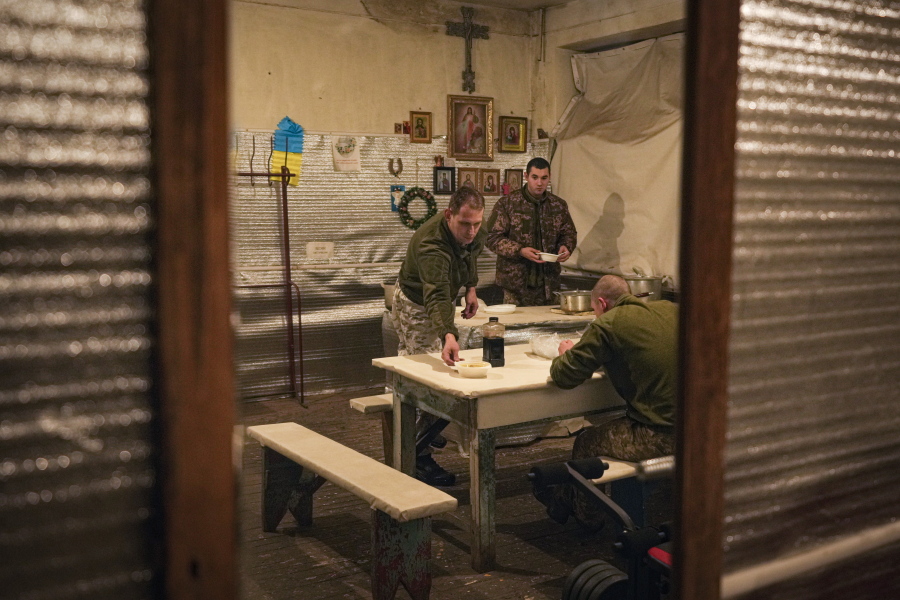 Ukrainian serviceman Ivan Skuratovskyi, left, prepares to have lunch before patrolling a frontline position outside Avdiivka, Donetsk region, eastern Ukraine, Friday, Feb. 4, 2022. President Volodymyr Zelenskyy is balancing worries about a military invasion with fears that alarm-ringing could wreck Ukraine's economy without hardly a shot fired, with a heightened awareness that Ukrainian public opinion is divided on how to handle the situation, especially when it comes to concessions toward pro-Russian separatists in the east.