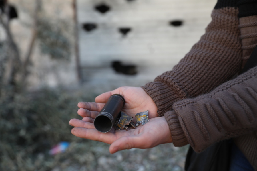 A child shows an empty bullet shell outside a destroyed house after an operation by the U.S. military in the Syrian village of Atmeh, in Idlib province, Syria, Thursday, Feb. 3, 2022. U.S. special forces carried out what the Pentagon said was a successful, large-scale counterterrorism raid in northwestern Syria early Thursday. Local residents and activists said civilians were also among the dead.