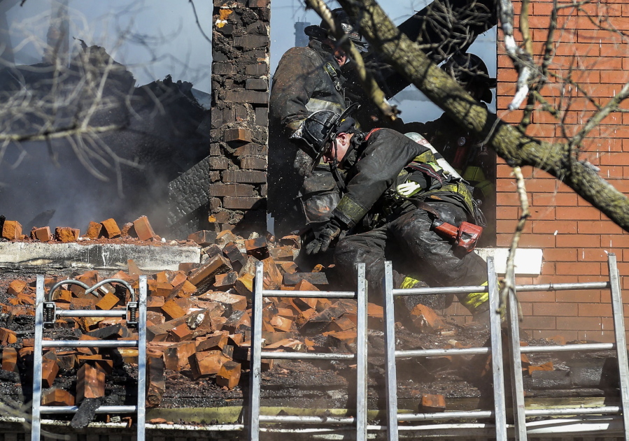 FILE - A firefighter reacts after a pile of bricks falls on him from a window eve as crews work to extinguish the fire in the structure in St. Louis, Mo., Thursday, Jan. 13, 2022. Leaders in St. Louis and Baltimore are considering changes in dealing with fires at vacant homes after firefighters in both cities died at abandoned structures in January. (Colter Peterson/St.