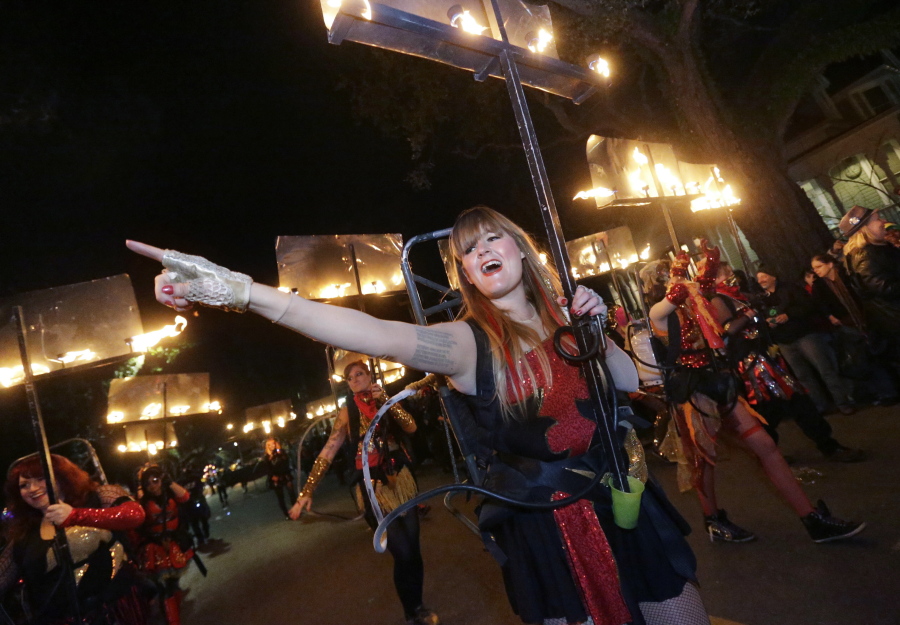 FILE - Sophie Woodruff, a member of the all-female flambeaux group, 'Glambeaux,' marches in the Krewe of Muses Mardi Gras parade in New Orleans, Thursday, Feb. 27, 2014. New Orleans residents, accustomed to catching beads, small toys or other trinkets tossed by parade float riders during Carnival season, were able to catch a new parade favor Thursday night:  rapid COVID-19 tests.