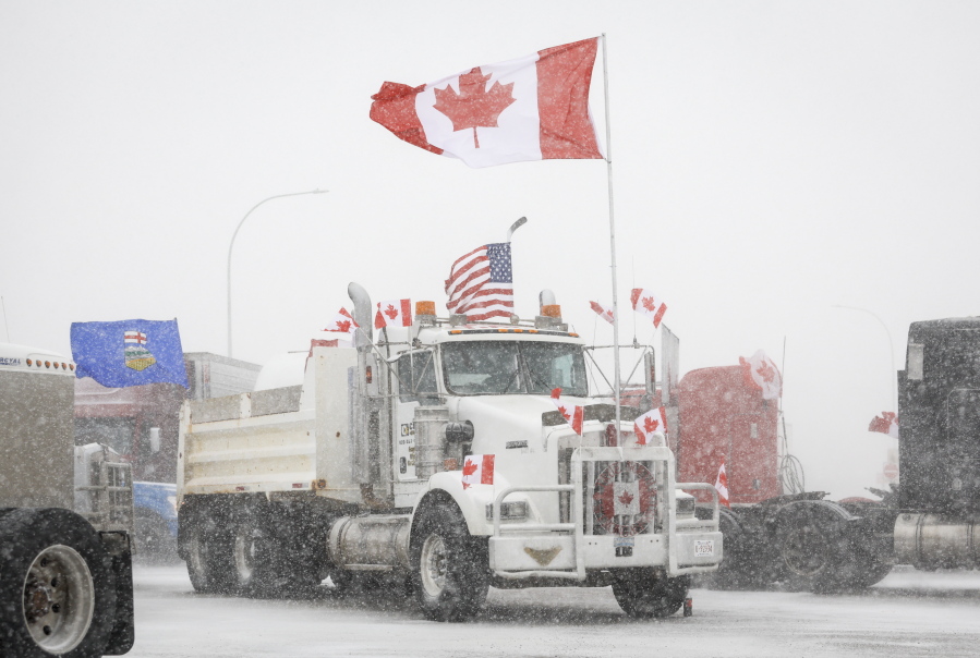 Anti-COVID-19 vaccine mandate demonstrators gather as a truck convoy blocks the highway at the busy U.S. border crossing in Coutts, Alberta, Canada, Monday, Jan. 31, 2022.