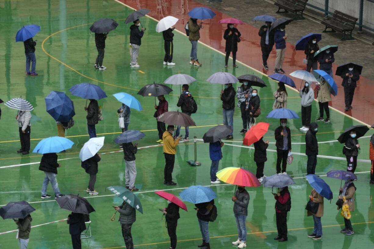 Residents line up to get tested for the coronavirus at a temporary testing center despite the rain in Hong Kong, Tuesday, Feb. 22, 2022.