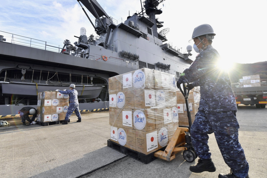 Members of the Japan Maritime Self-Defense Force load emergency relief aid bound for Tonga to a ship in Kure, near Hiroshima, western Japan, Jan. 24, 2022. The Pacific archipelago nation of Tonga is in lockdown after detecting its first community transmission of COVID-19, which appears to have been brought in by aid workers delivering supplies of fresh water and medicine after last month's volcanic eruption and tsunami.