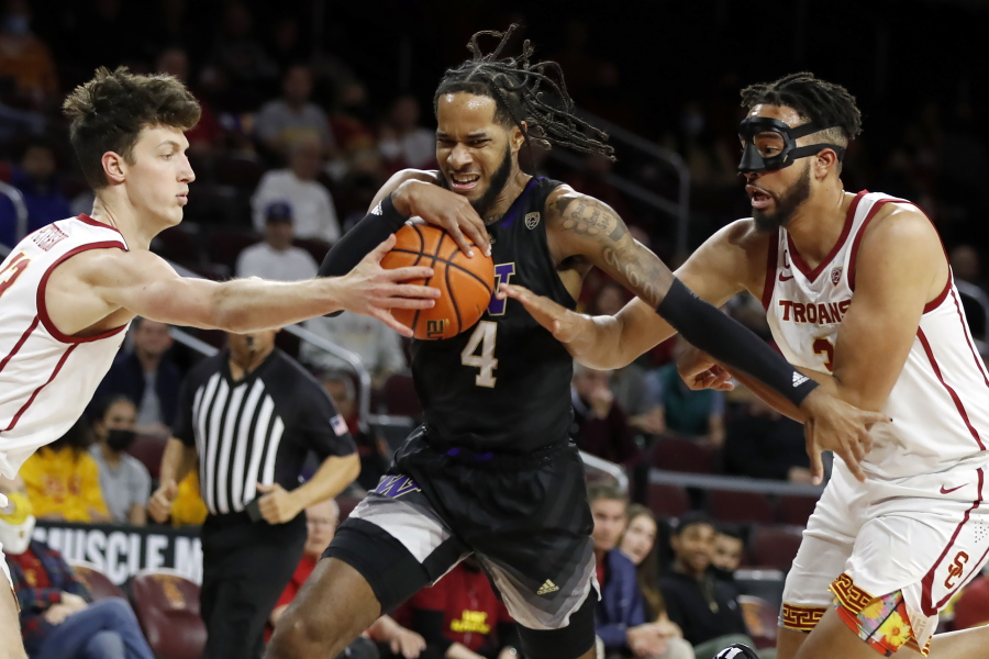 Washington guard PJ Fuller, center, drives between Southern California guard Drew Peterson, left, and forward Isaiah Mobley during the first half of an NCAA college basketball game in Los Angeles, Thursday, Feb. 17, 2022.