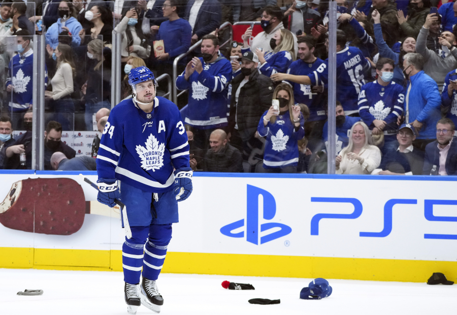 Toronto Maple Leafs forward Auston Matthews (34) celebrates his hat trick as fans throw their hats on the ice while during the third period of an NHL hockey game against the Seattle Kraken, Tuesday, March 8, 2022, in Toronto.
