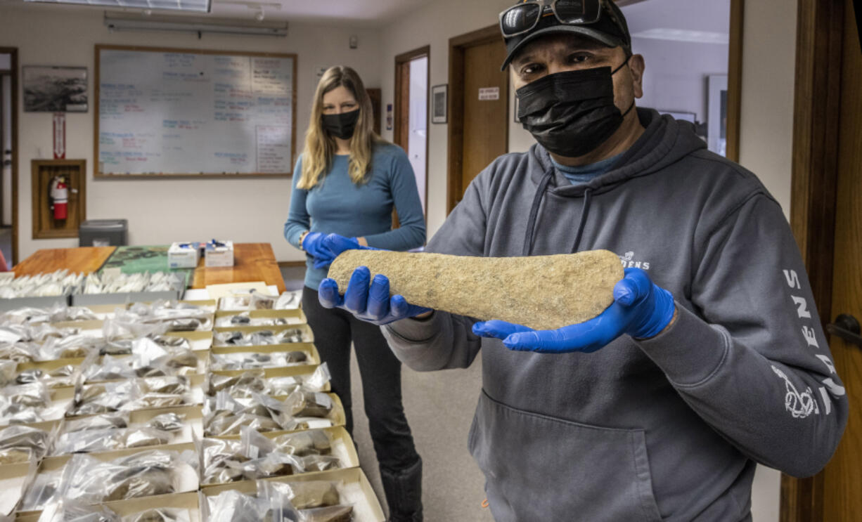 Scott Schuyler, policy representative for the Upper Skagit tribe for natural and cultural resources, holds a fish club that is part of the artifacts discovered near Ross Lake being turned over to the tribe, on March 16. Andrea Weiser, senior archaeologist for Seattle City Light, is at left.