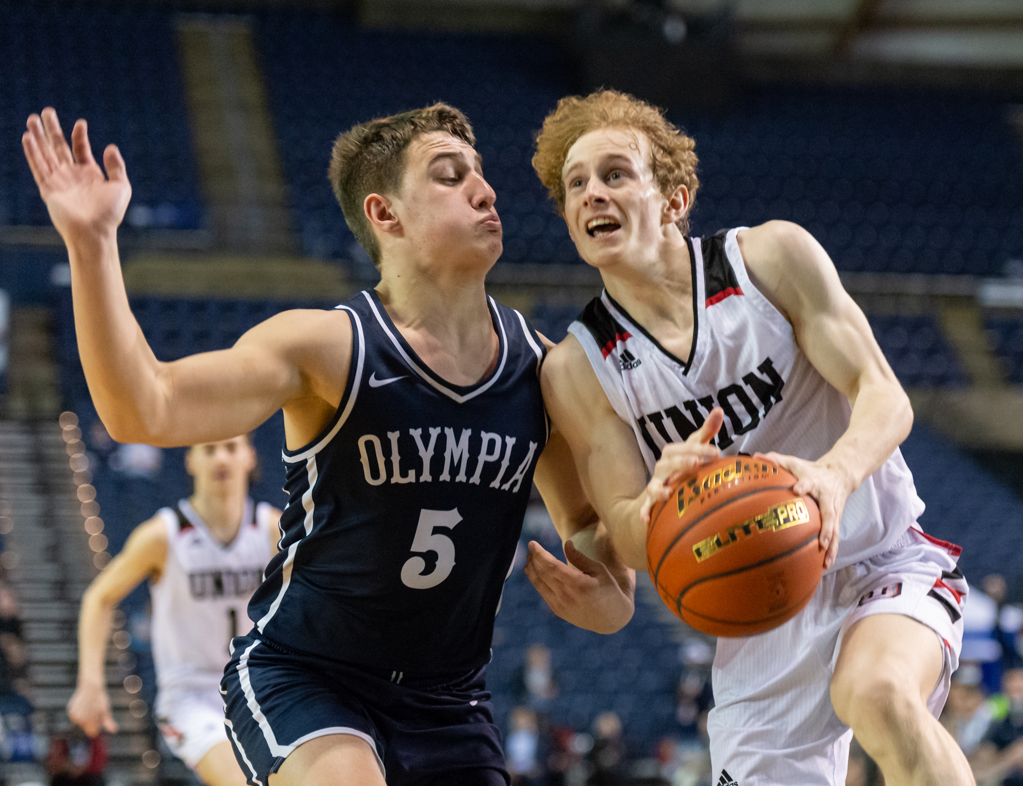 Union's Bryson Metz initiates contact with Olympia's Mason Juergens on his way for layup in a 4A State Boys Basketball third-place game on  Saturday, March 5, 2022, at the Tacoma Dome.