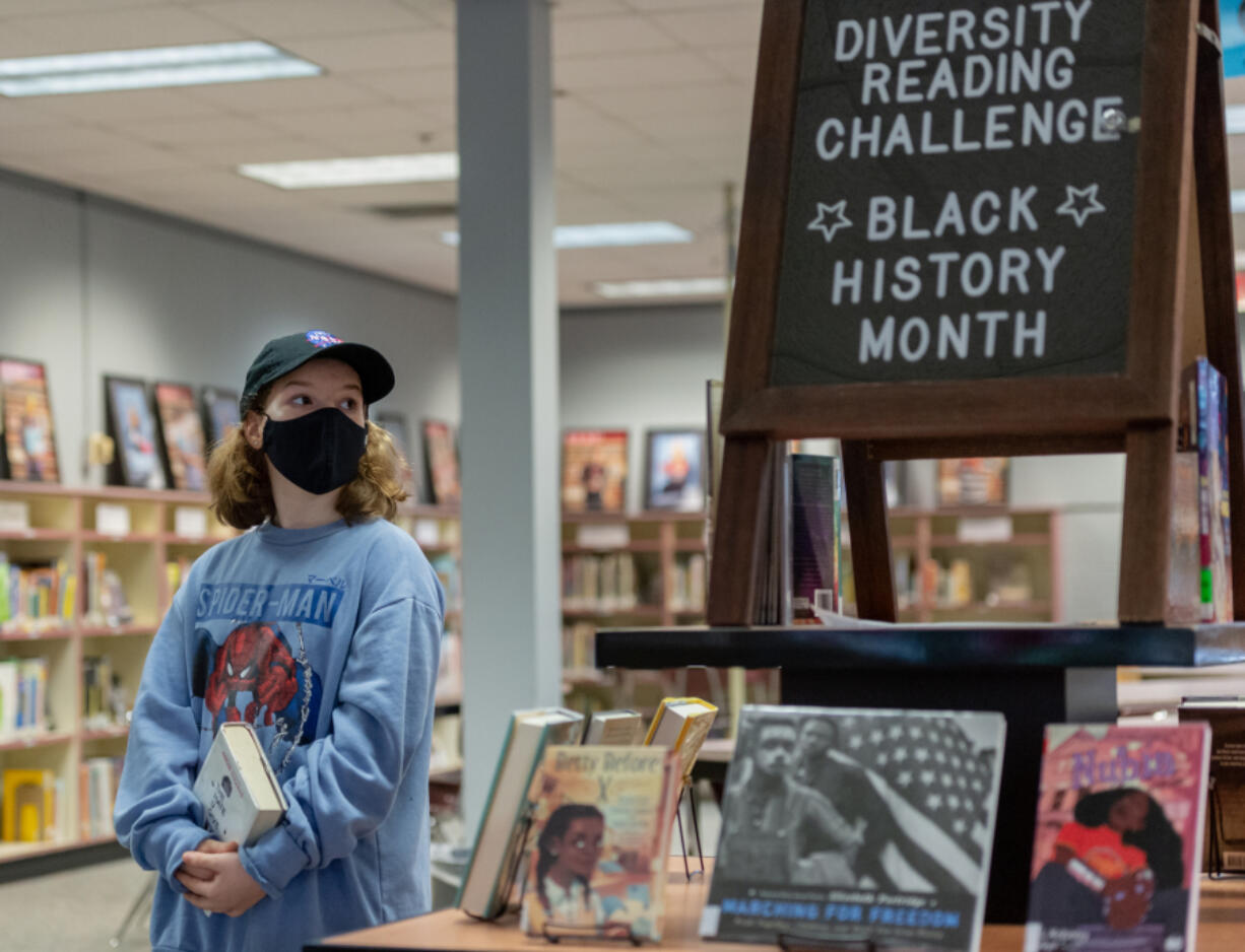 Eighth-grader Nola Bouffard looks over the selection of books as part of the diversity reading challenge in the library at Jason Lee Middle School in Hazel Dell.