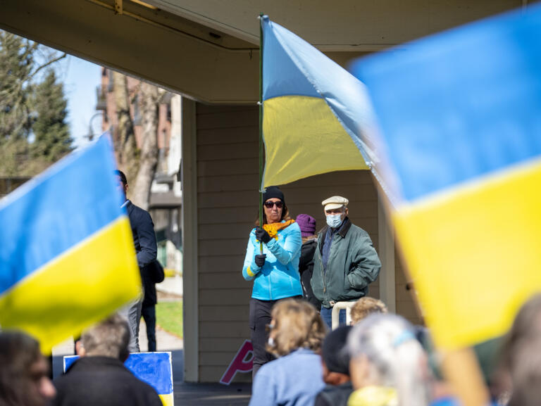 Natalia Rieland, center, of Vancouver, waves a large Ukrainian flag in front of a crowd on Sunday during a rally at Esther Short Park.
