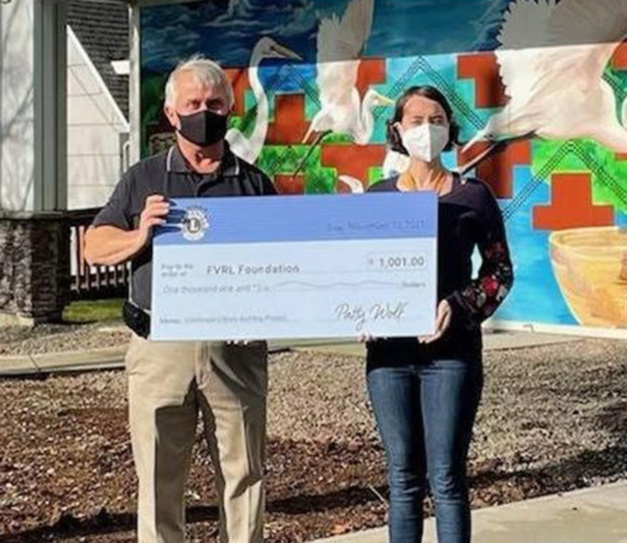 Camas Lions Club President Brian Scott presents Washougal Community Library Branch Manager Rachael Ries with a $1,001 check to help fund the new library building.