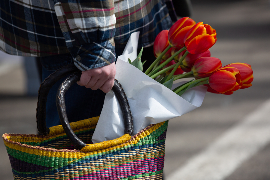 A shopper carries a basket with fresh tulips Saturday at the Vancouver Farmers Market.