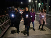 In a photo provided by Multnomah County, Multnomah County Chair Deborah Kafoury, center, leads the illuminated walk over the Hawthorne Bridge with Commissioners Lori Stegmann, left, Jessica Vega Pederson, second from right, and Susheela Jayapal, right, Thursday, March 10, 2022, in Portland, Ore., during an event held two years after the first confirmed case of COVID-19 in Portland.